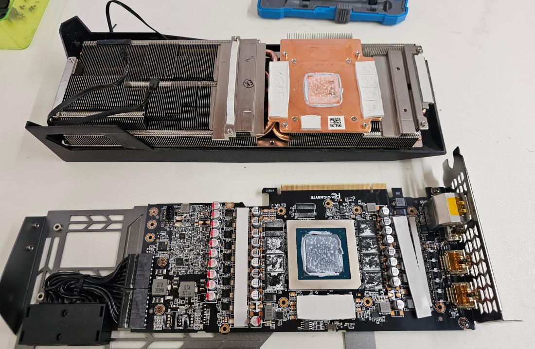 Atelier de réparation d'AdrianPCMaster à Sierre : carte graphique démontée sur l'établi, dissipateur, circuit imprimé et outillage de précision.